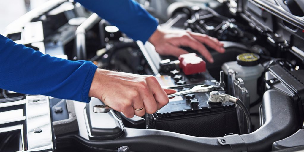 A GMC technician working on a car battery.